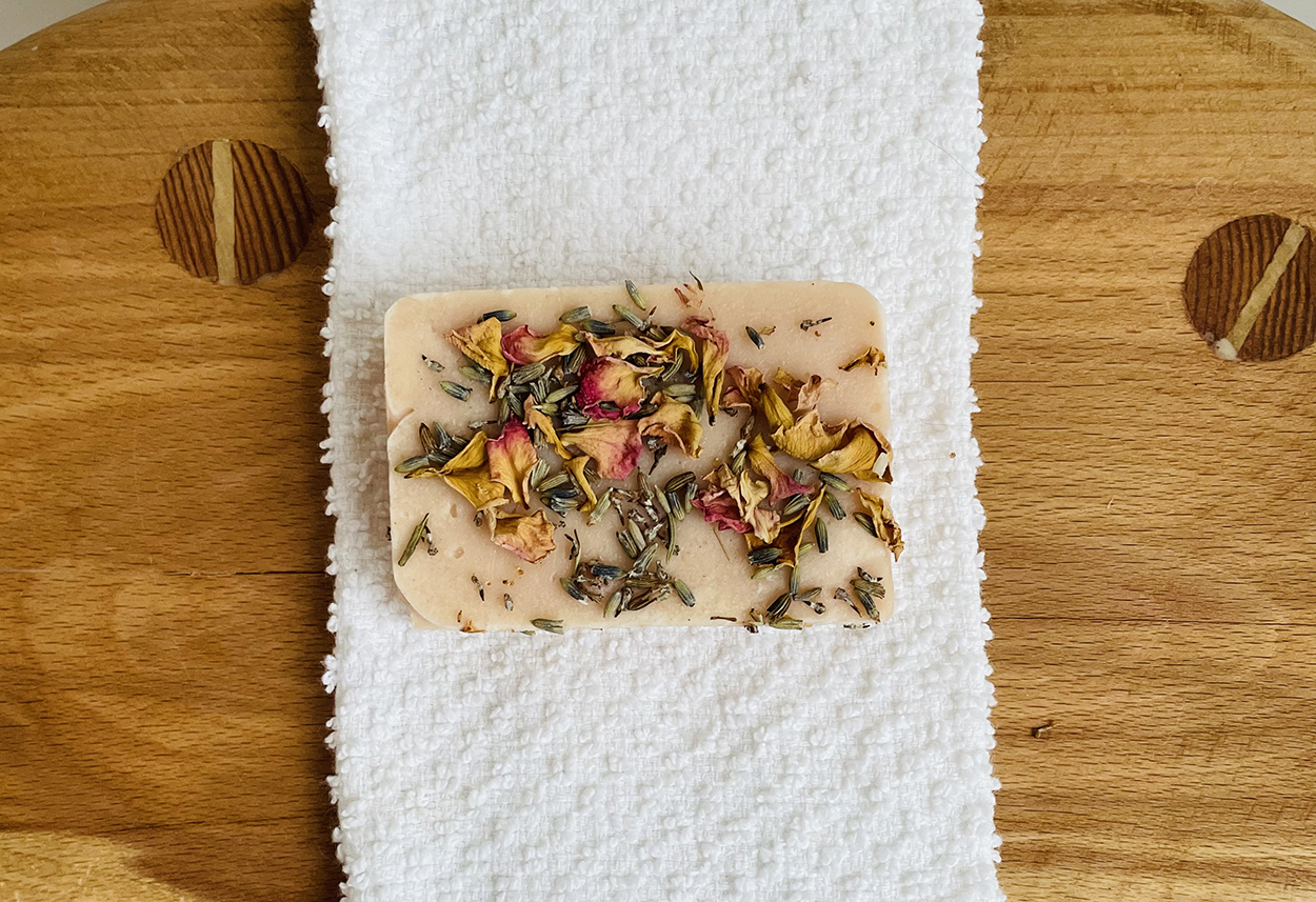 A bar of pink soap with dried petals on it
